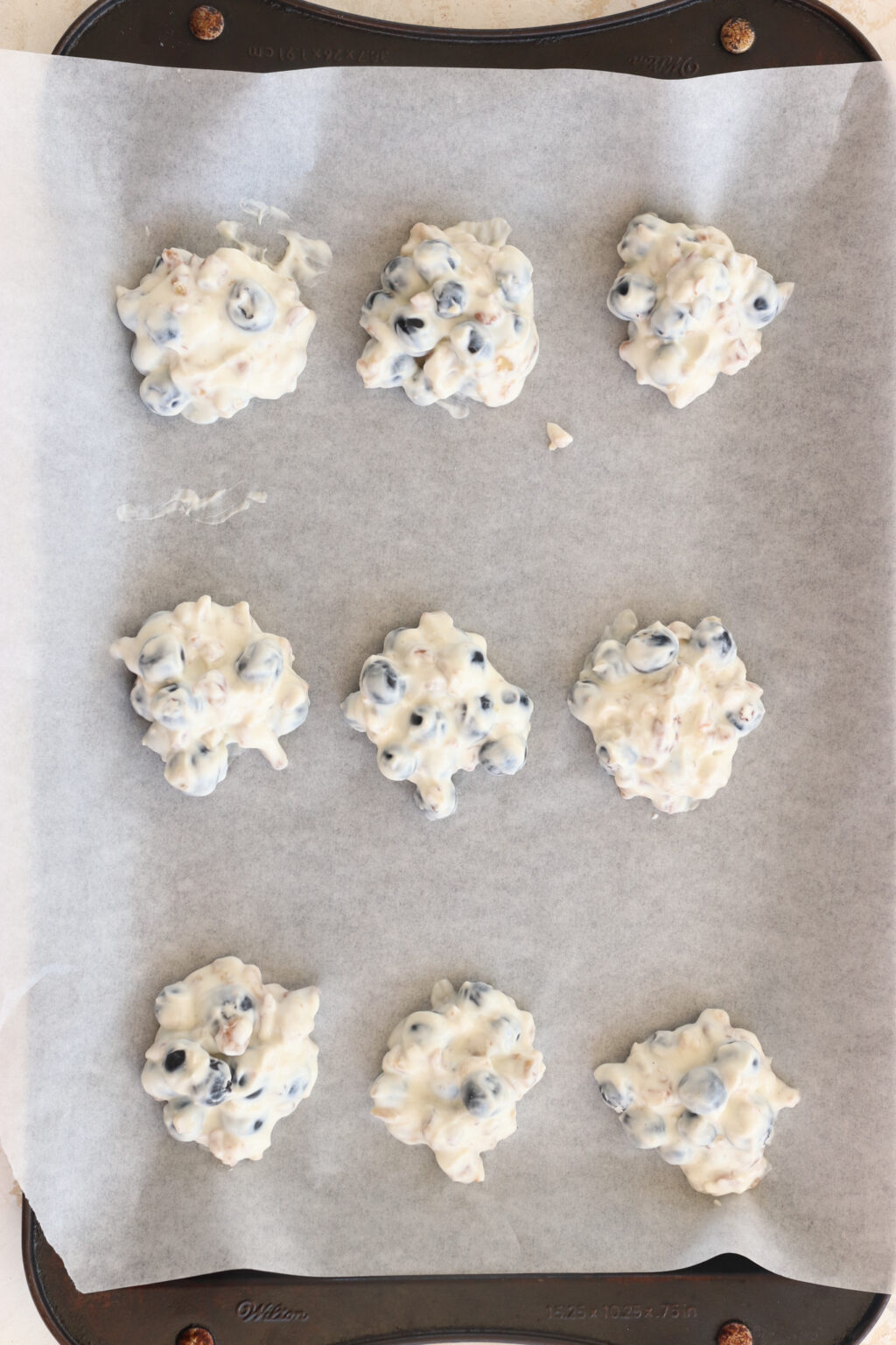 Frozen Blueberry Greek Yogurt Clusters on a pan with parchment paper before being dipped in chocolate