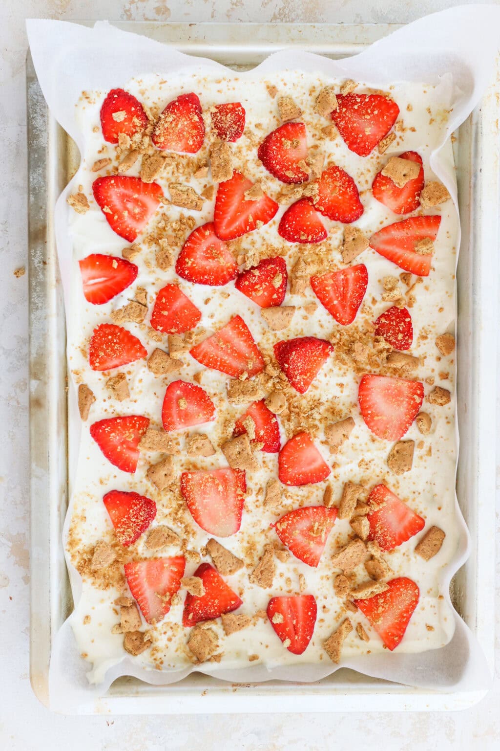 High Protein Frozen Greek Yogurt Cheesecake Bark with Strawberries on a sheet pan with parchment paper