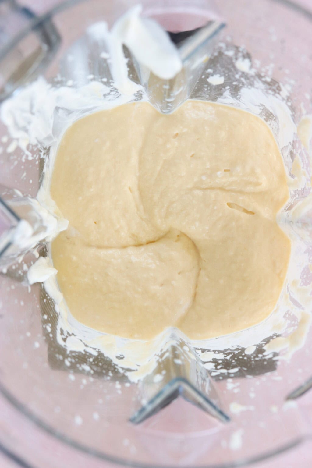 Ingredients for high protein tropical smoothie bowl with Greek yogurt blended in a blender, including Greek yogurt, mango, riced cauliflower, lime juice, milk of choice