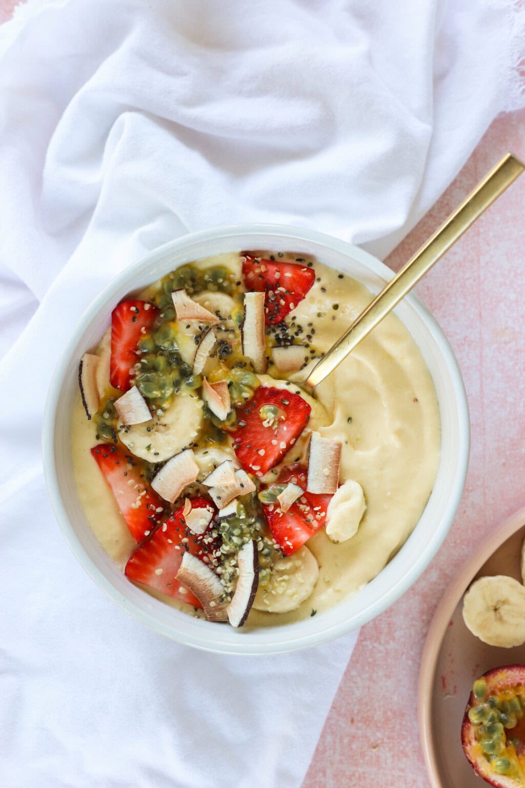High Protein Tropical Smoothie Bowl with Greek Yogurt in a white bowl with a gold spoon and white tablecloth