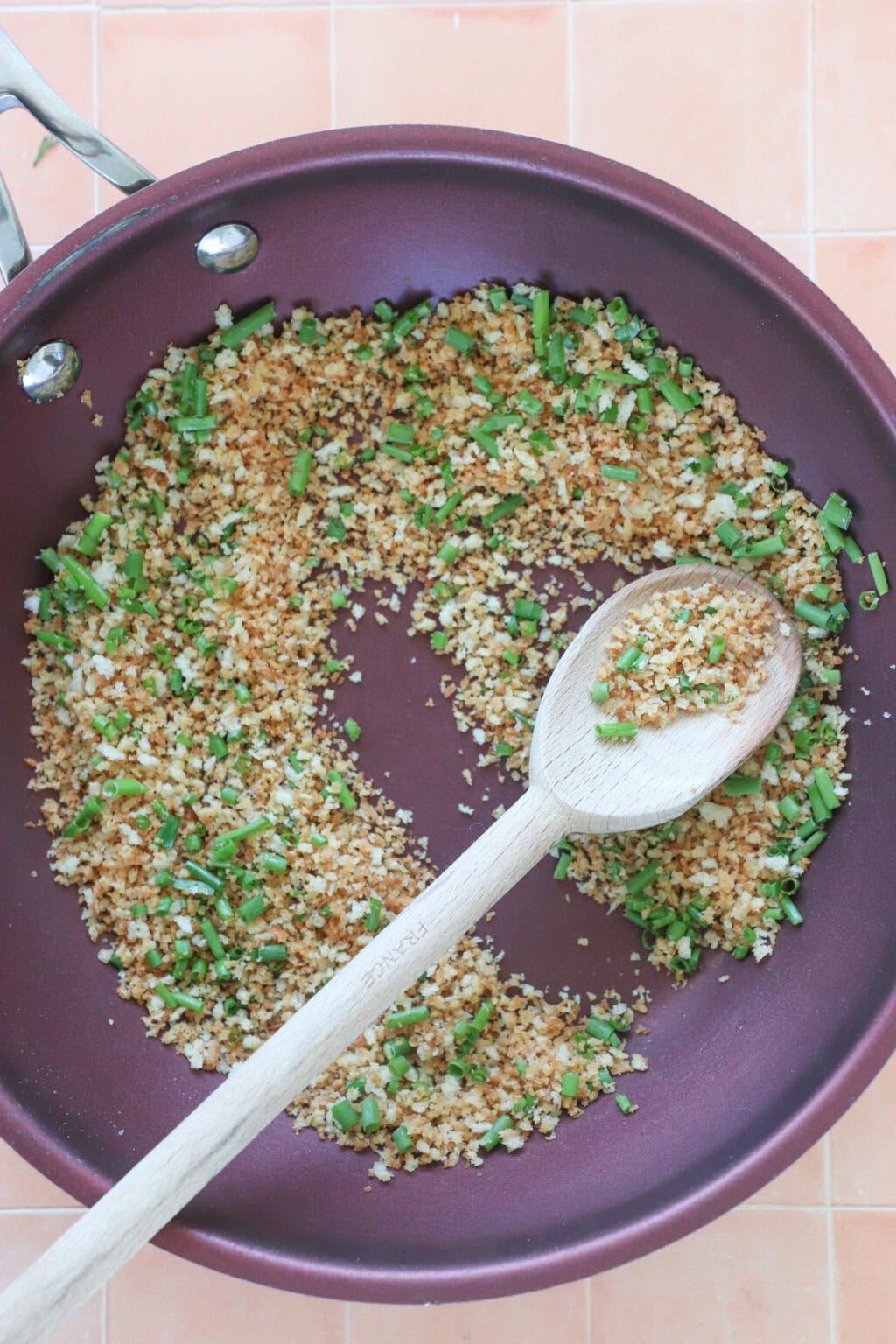 Panko bread crumbs and chives in a red pan being stirred