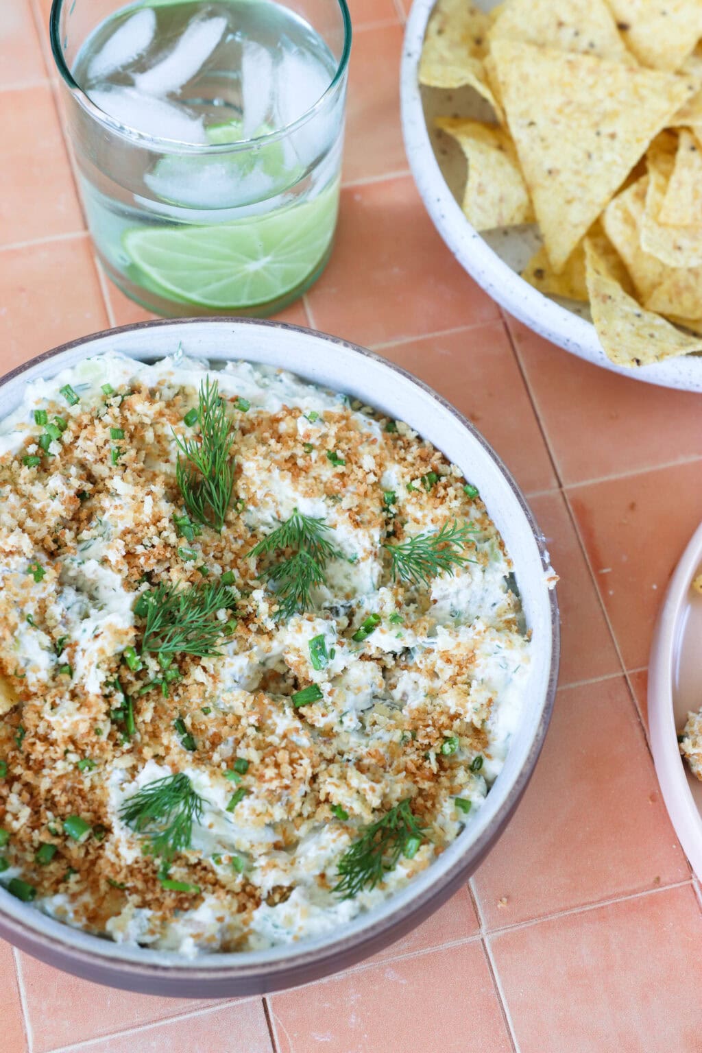 Seriously Good "Fried" Pickle Dip with Greek Yogurt in a white bowl with some dishes on the side