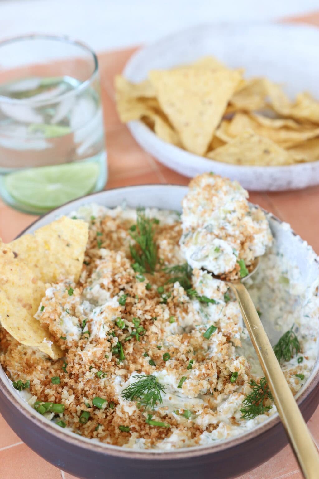 Seriously Good "Fried" Pickle Dip with Greek Yogurt in a white bowl with a scoop on a spoon and dishes on the side
